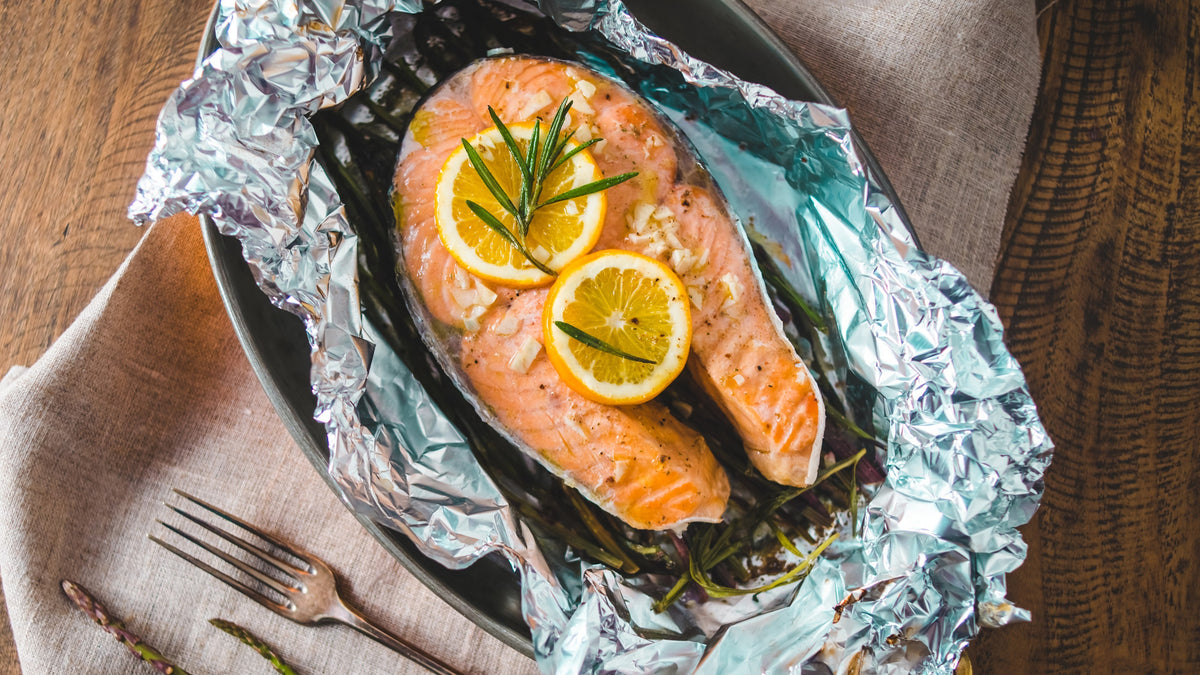 Lachsfilet mit Zitronenscheiben und Rosmarin im offenen Folienpäckchen