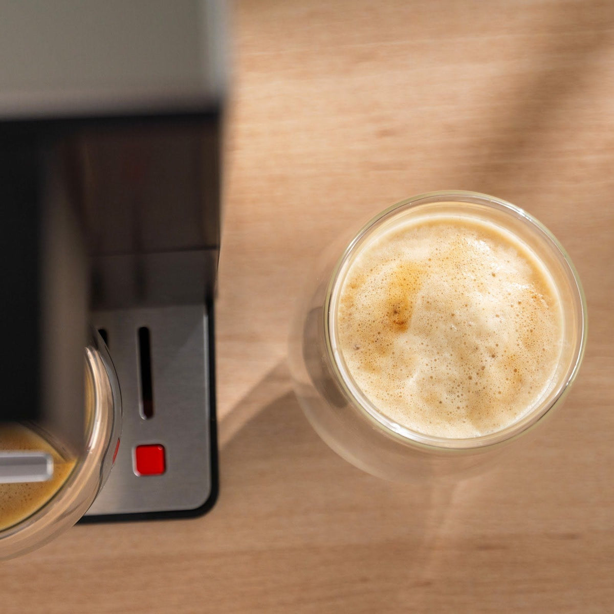 Latte in einem Glas von oben, mit einer hellen, dichten Schicht Milchschaum