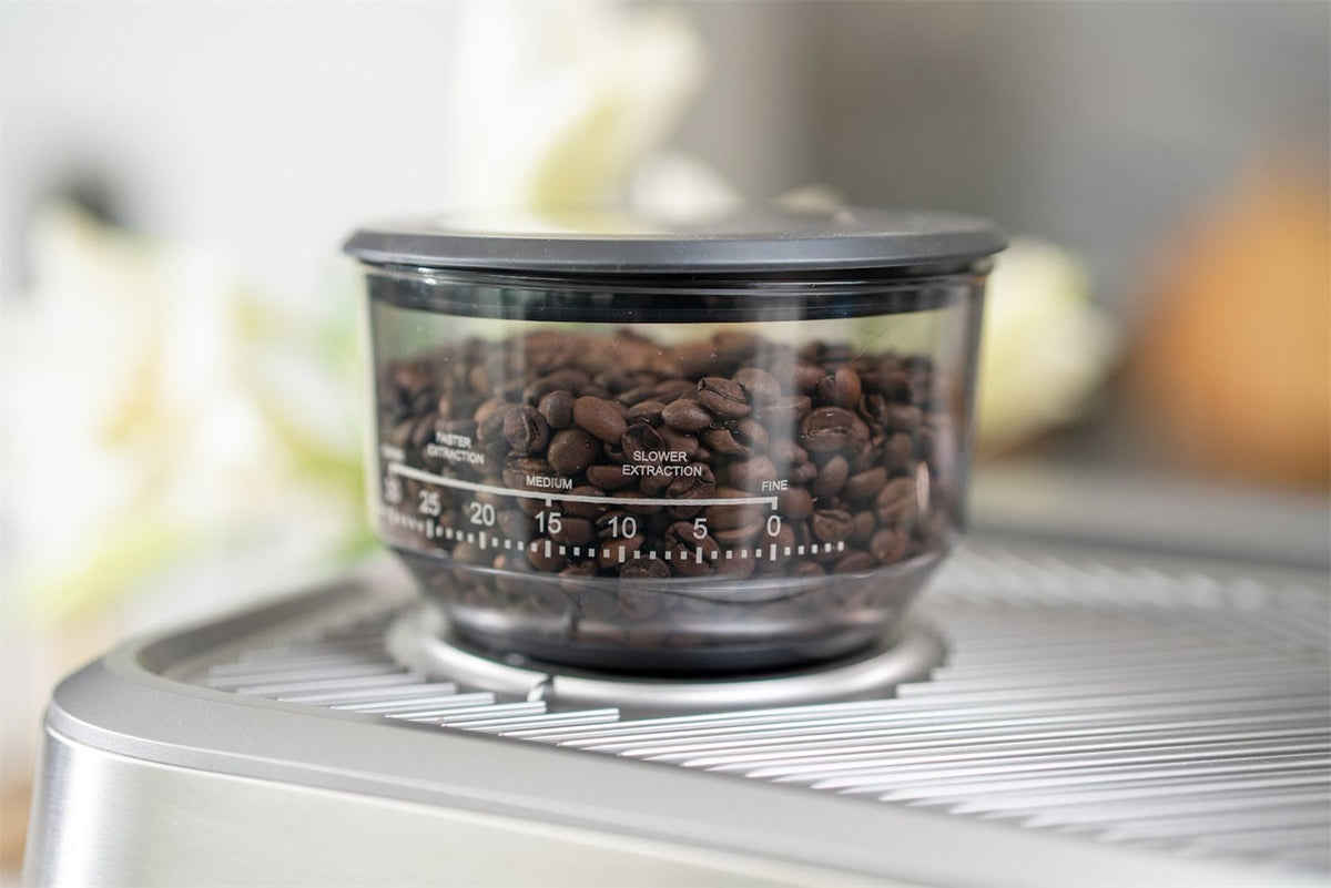 Bohnenbehälter mit Kaffeebohnen und einer Skala von fein bis grob auf einer Espressomaschine aus Edelstahl
