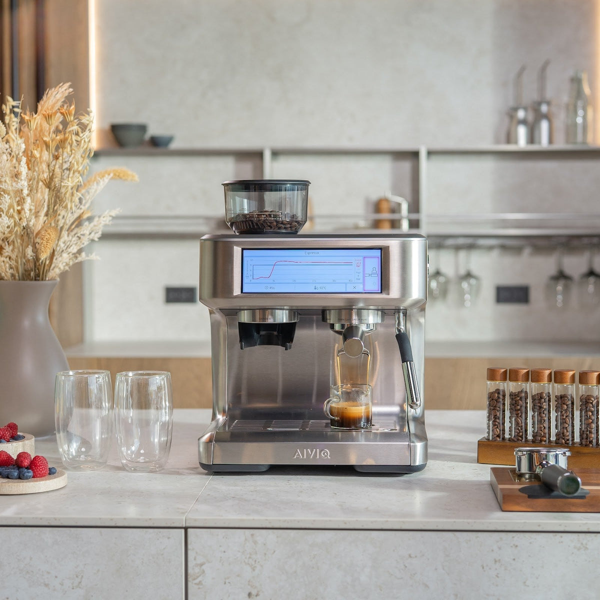 Aspire Expert auf einer hellen Arbeitsplatte in einer Küche mit Holzpaneelen und offenen Regalen. Ein Espresso läuft in einen kleinen Messbecher, während der Bildschirm eine Druckkurve zeigt.