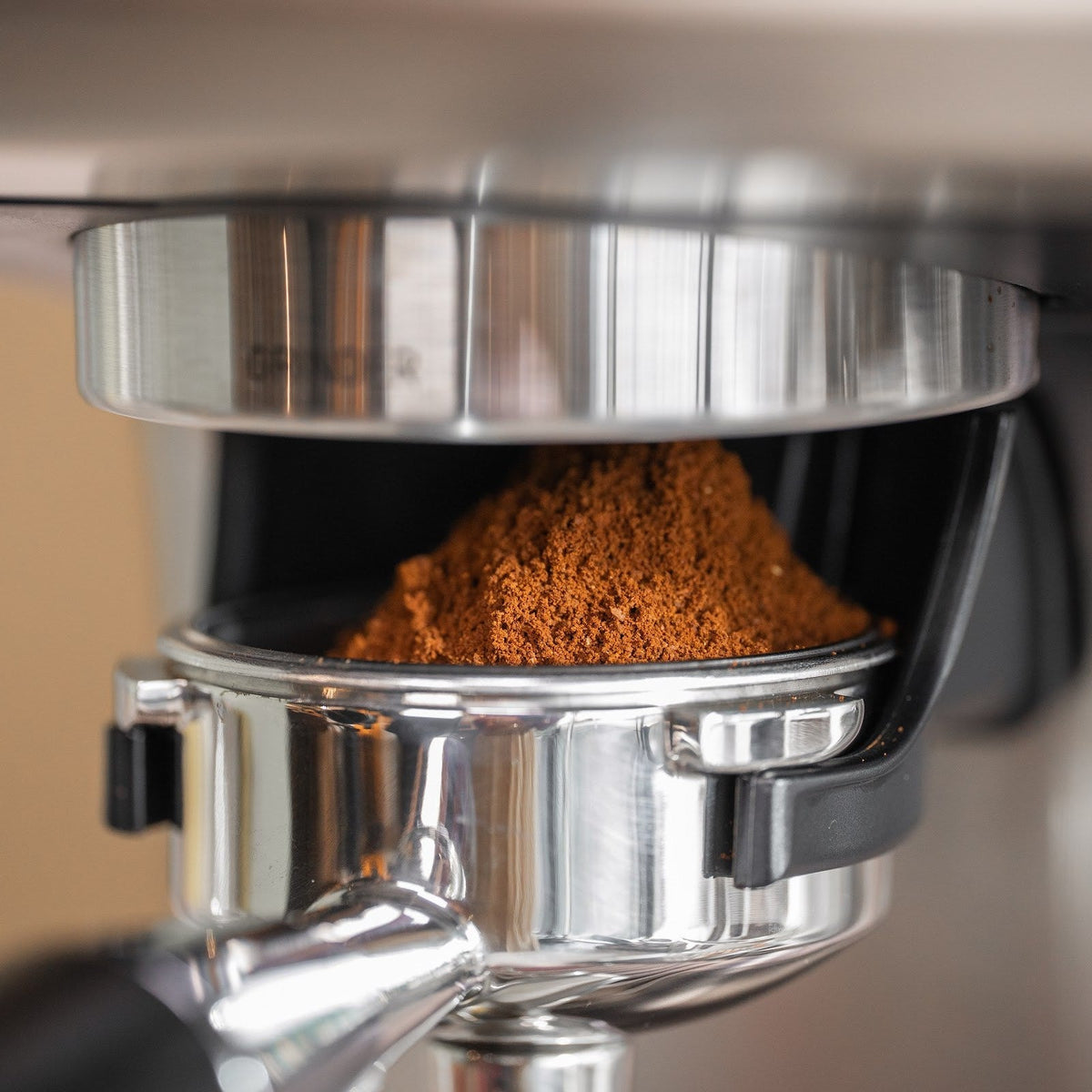 Frisch gemahlener Kaffee als Häufchen im Siebträger, der im Halter unter dem Mahlwerk der Aspire Expert steht. Die Waage sitzt im Halter.